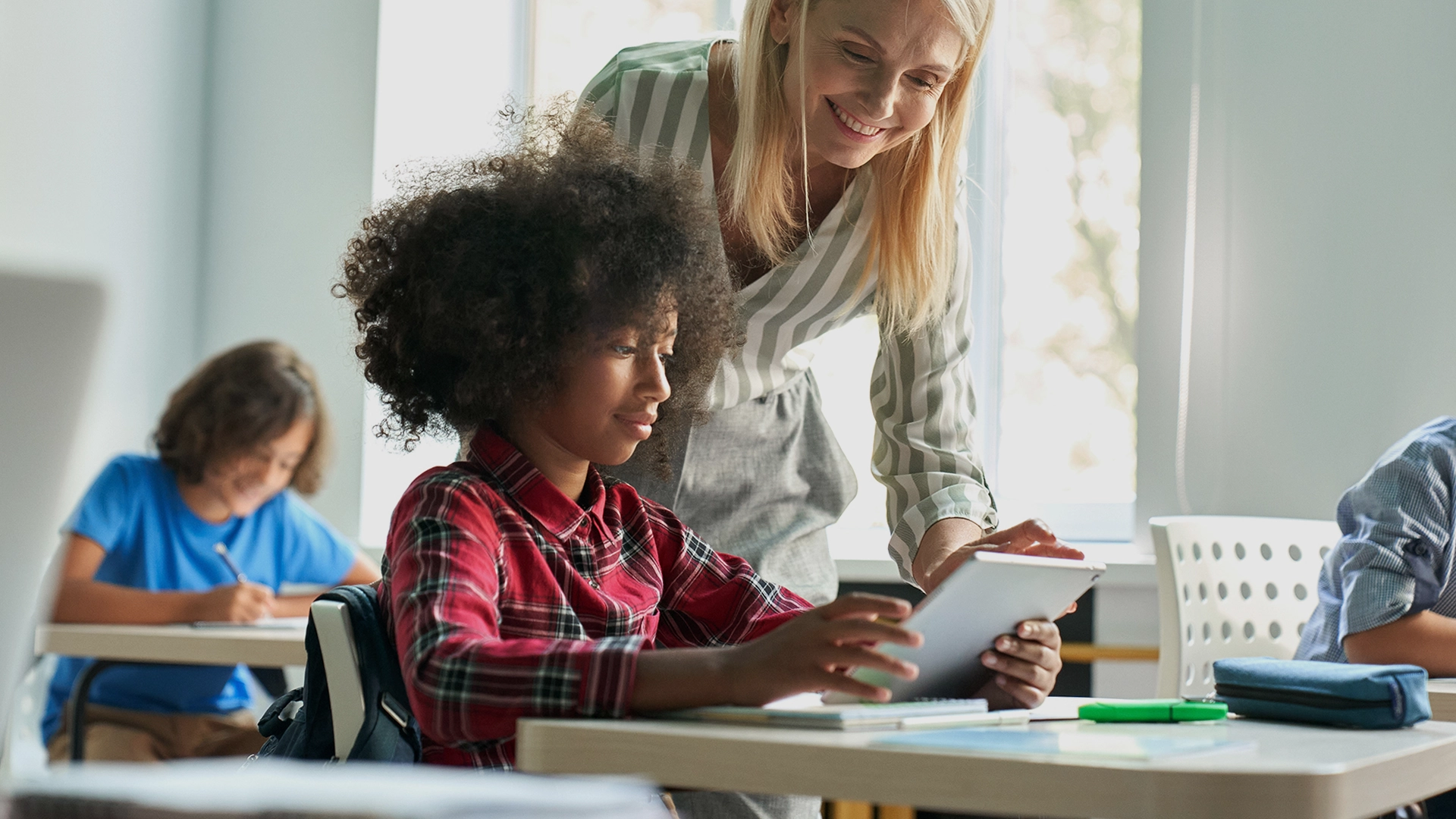 An educator helps a middle school student use Istation in a classroom.