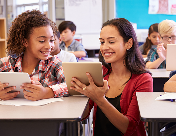 Una profesora con una estudiante usando un iPad en el salón de clase