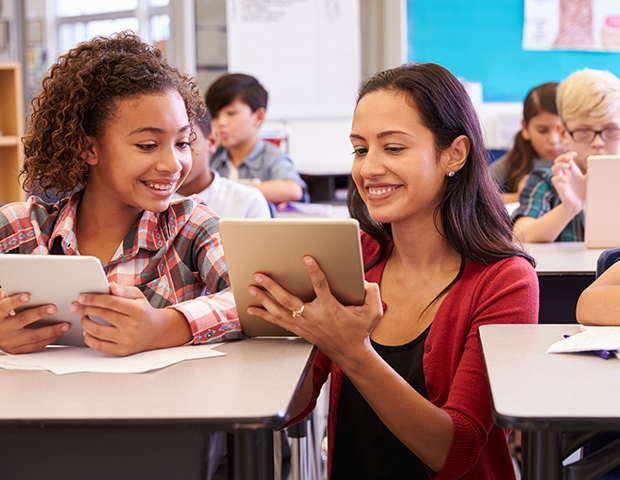 Female educator with student using iPad in classroom