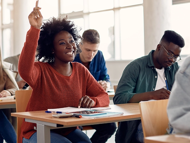 High-Schooler-Sitting-Desk-Hand-Raised-640x480