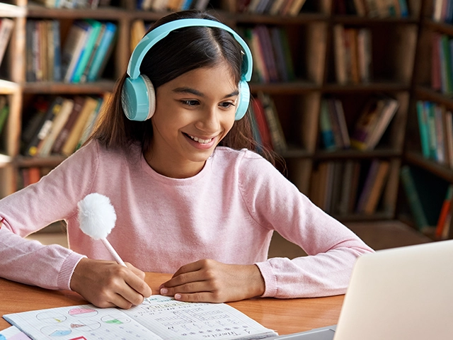 Una estudiante trabajando con audífonos y una computadora portátil