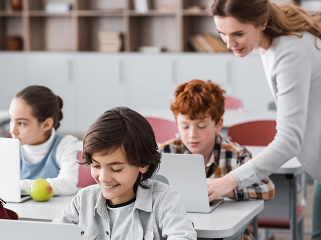 Teacher-Helping-Schoolboy-On-Laptop-640x480